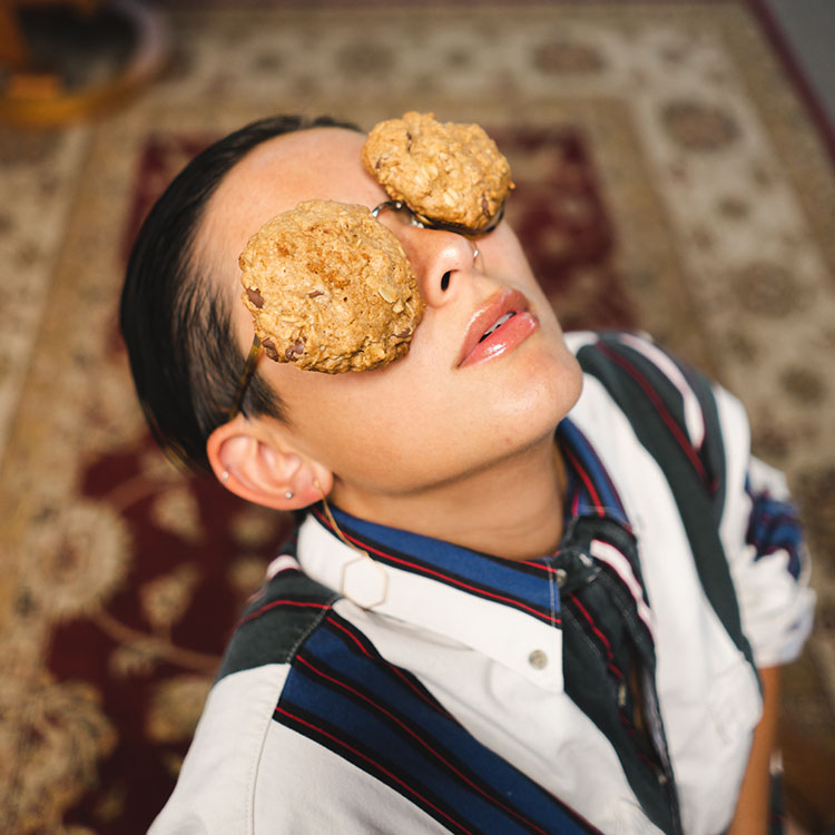 Person with chocolate chip cookies on their eyes.