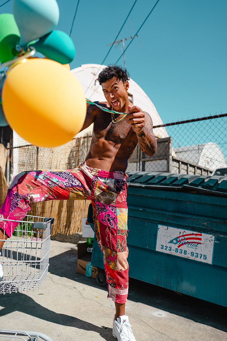 Topless man throwing balloons toward camera.